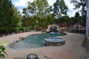 Nautical-themed hybrid swimming pool with raised spa, sunshelf, slide, grotto, and pizza oven