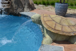 Carved concrete turtle by Karen of Legendary Escapes creates a fountain into the vinyl liner swimming pool with a reef liner.